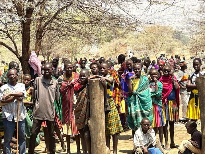 Women, men and children gathered under the trees on distribution day