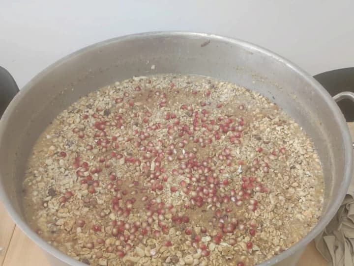 The pot of aşure topped with pomegranate seeds and nuts